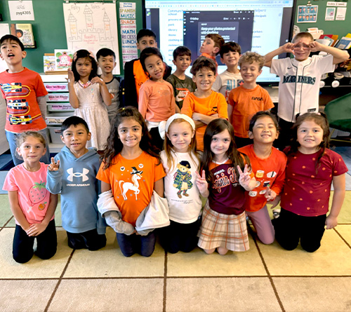 Students wearing orange performing a dance routine on stage