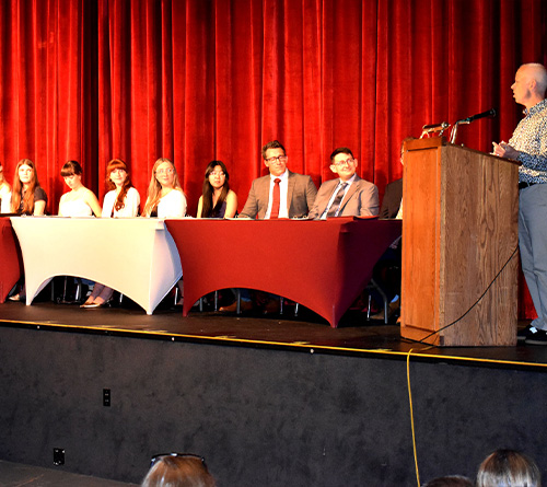 Students on stage holding certificates at Tri-M Music Honor Society ceremony