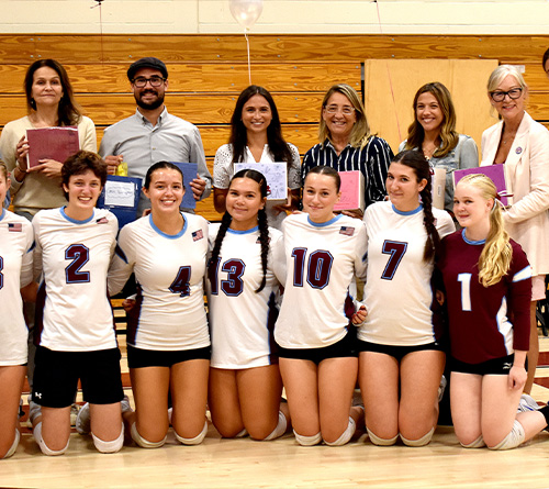 Students holding certificates while standing on stage.