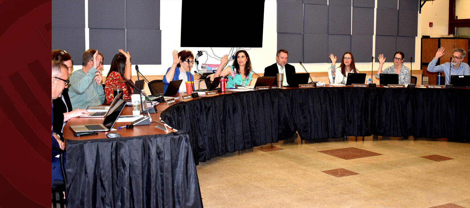 School board members voting during a meeting with raised hands