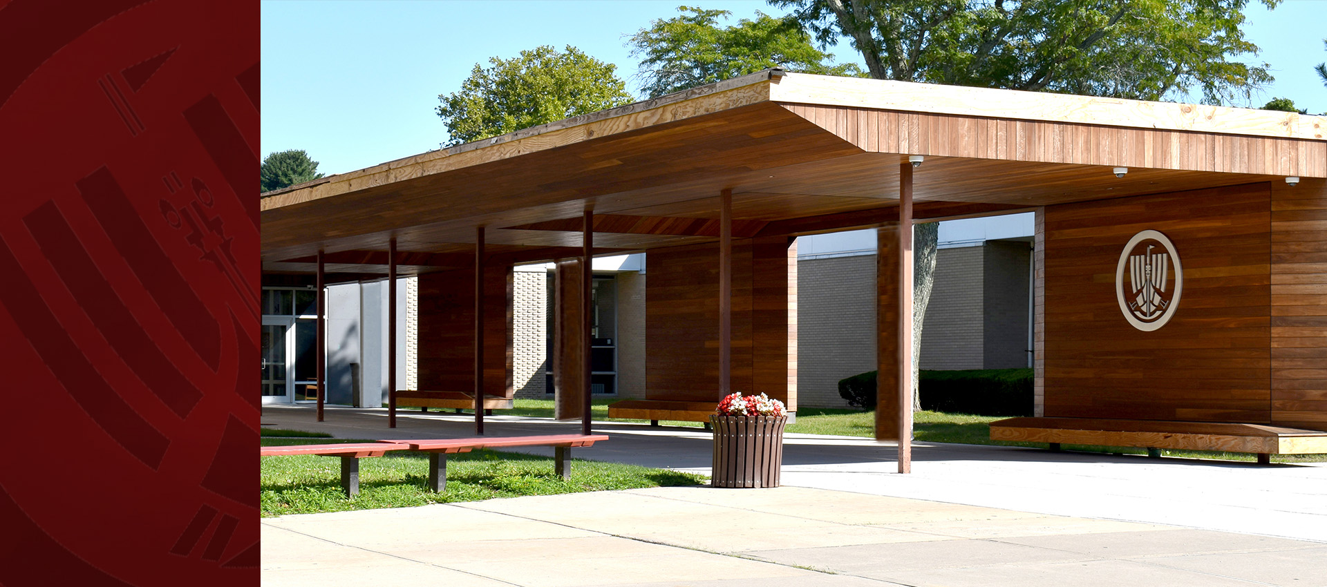 North Shore Schools high school entrance featuring a modern wooden pavilion, school logo, benches, and landscaped campus grounds.