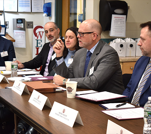 Group of people seated around a table at a meeting.