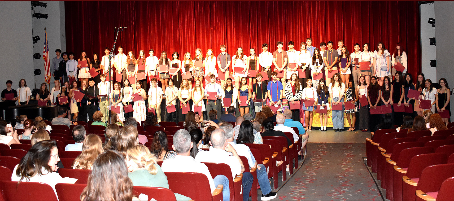 Large group of high school students on stage showing certificates