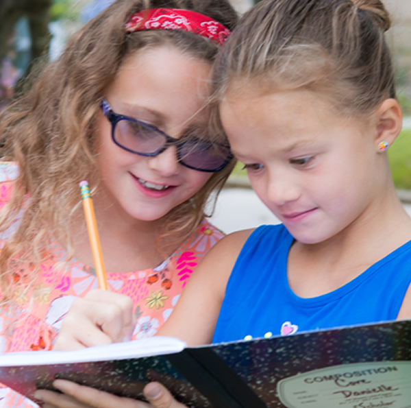 Two Young Students Writing in Composition Book